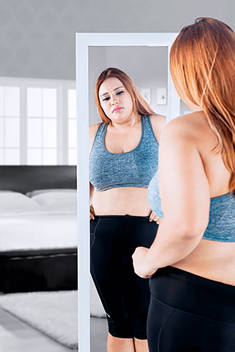 Woman looking in the mirror after weight gain